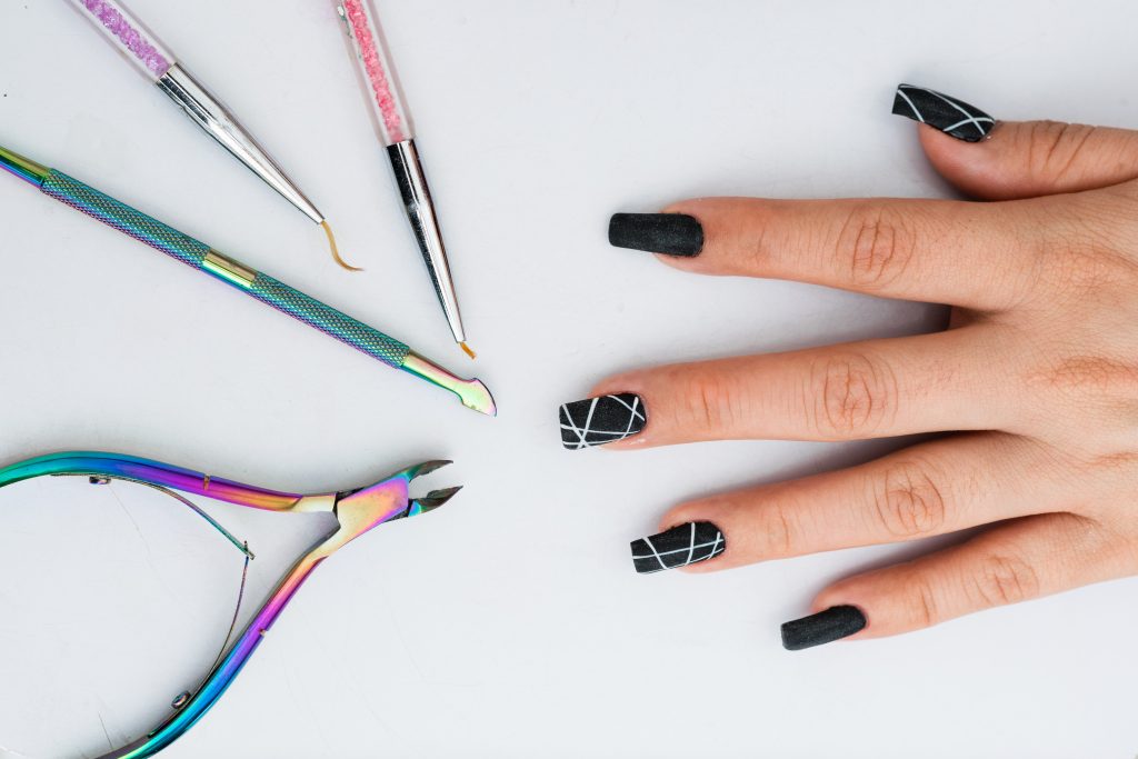 Unhas decoradas, em frente a ferramentas de manicure.
